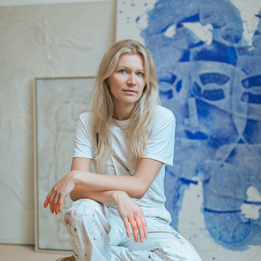 Portrait von Isabel Bernat im Atelier vor einer Leinwand mit Relief-Technik mit blauer abstrakter Gesichtsform.