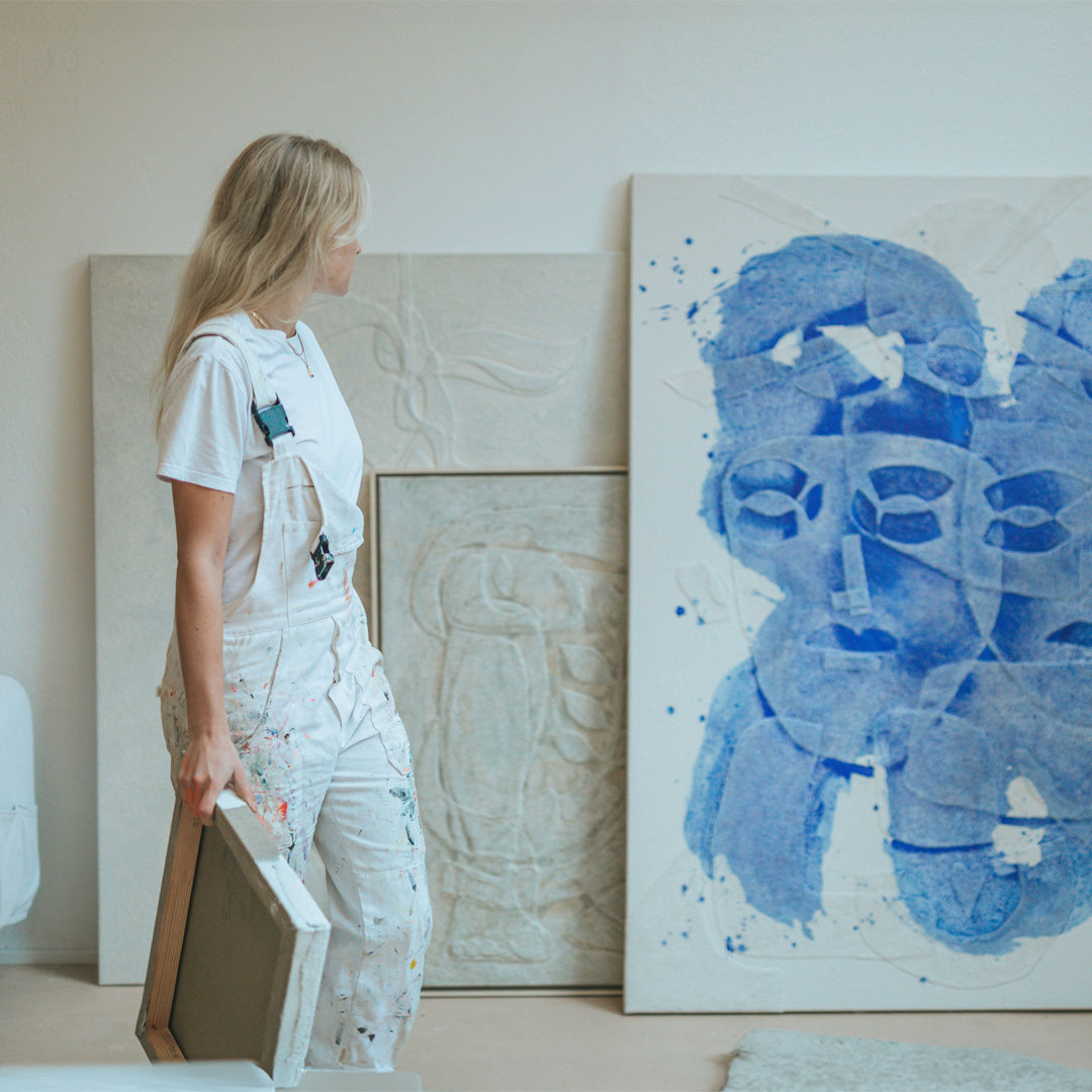 Isabel Bernat im Atelier vor blauer abstrakter Gesichtsform aus Relief-Technik auf Leinwand.