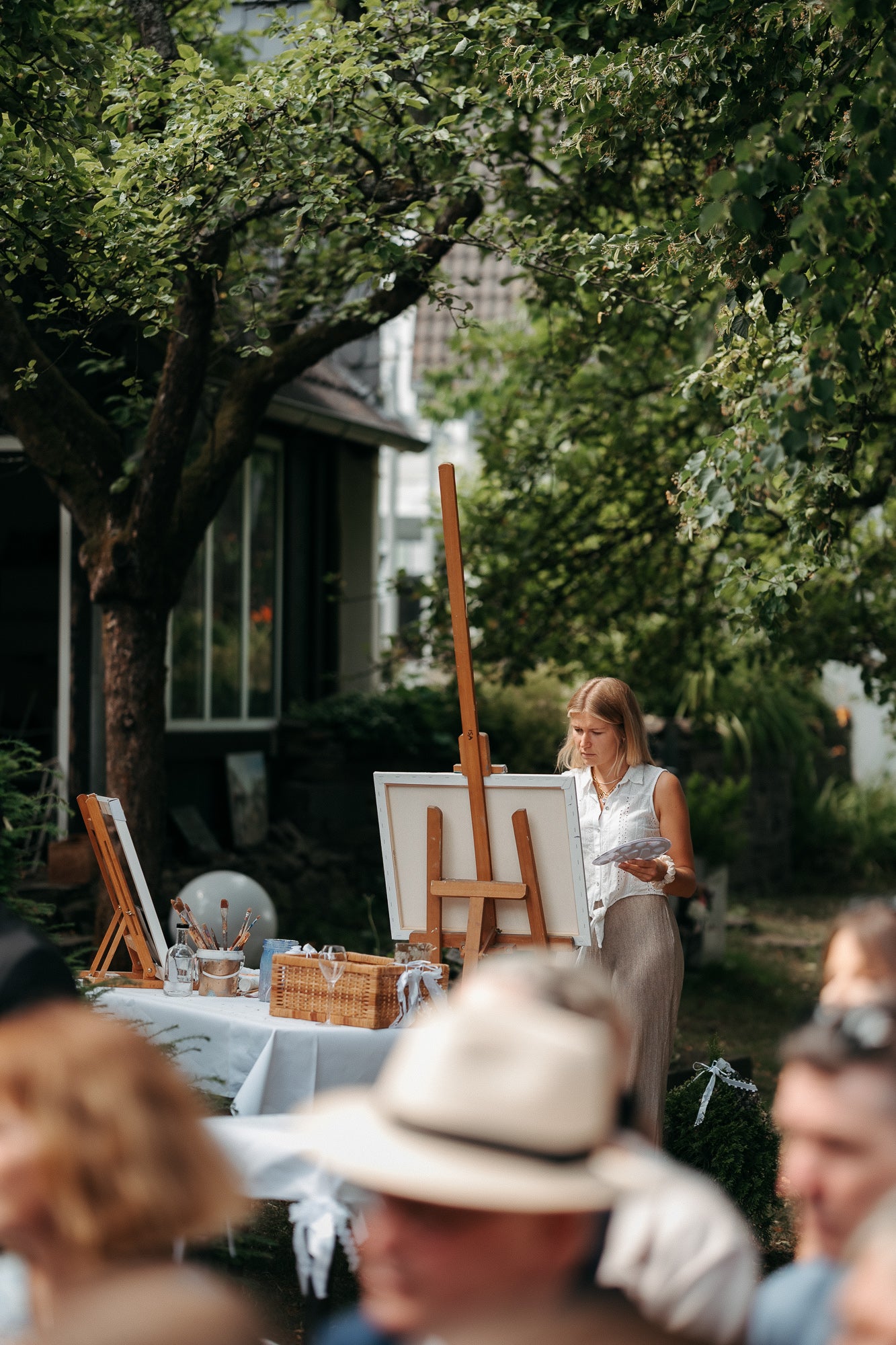 Isabel Bernat malt im Freien an einer Staffelei ein Live-Gemälde bei einer Hochzeit.