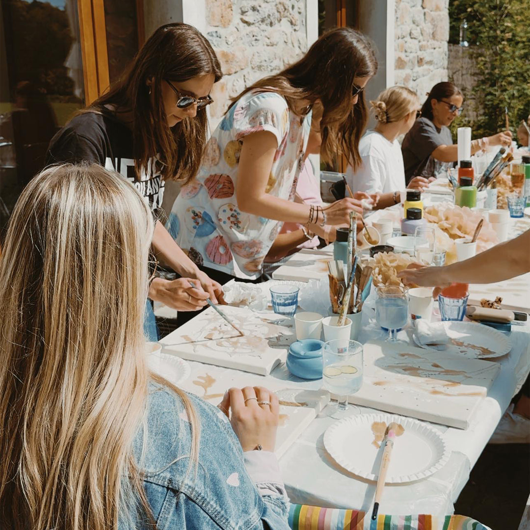 Teilnehmende an einem Kreativ-Workshop malen gemeinsam an einem Tisch.