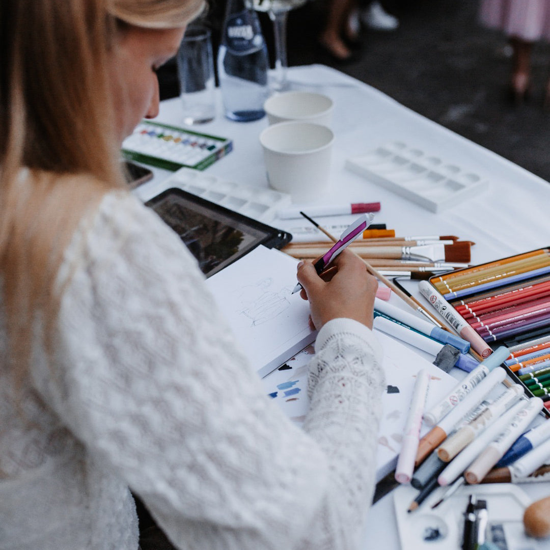 Isabel Bernat beim Zeichnen mit Buntstiften an einem Tisch bei einer Live-Illustration.
